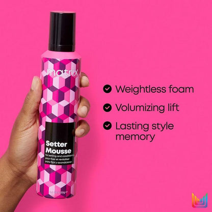 Hand holding a bottle of Matrix Setter Mousse against a pink background with product features listed.